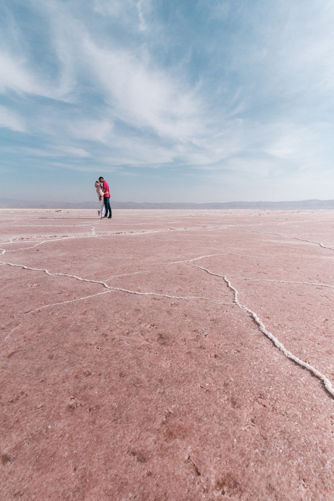 Happy relaxed travelers enjoying unusual scenery of pink salt lake in sunny day