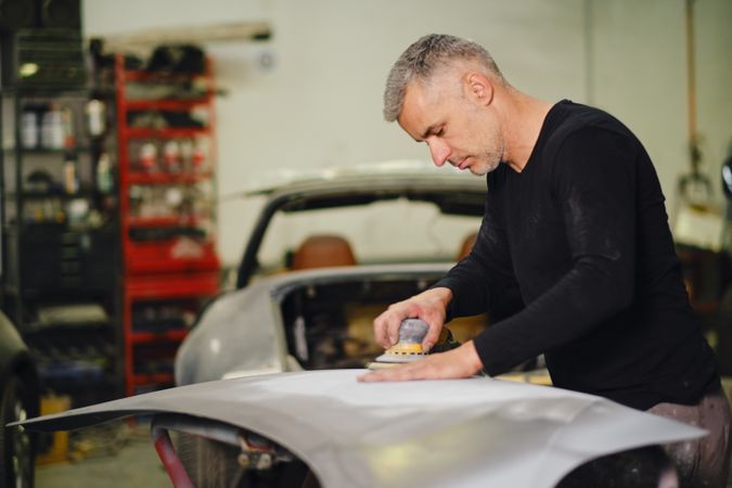 Mechanic grinding paint from car detail