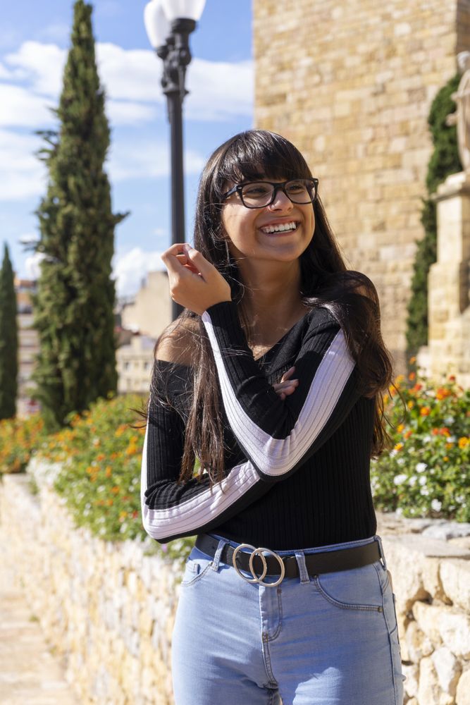 Portrait of woman in glasses smiling while looking at camera standing in the street