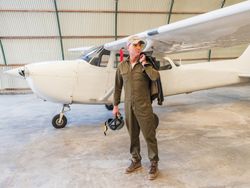Confident pilot beside retro plane in hangar