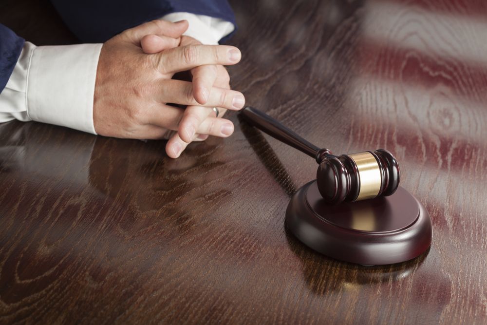 Judge Rests Hands Behind Gavel with American Flag Table Reflection