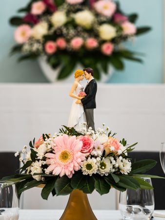 Wedding table decorations. Flowers, figurines of the bride and groom.