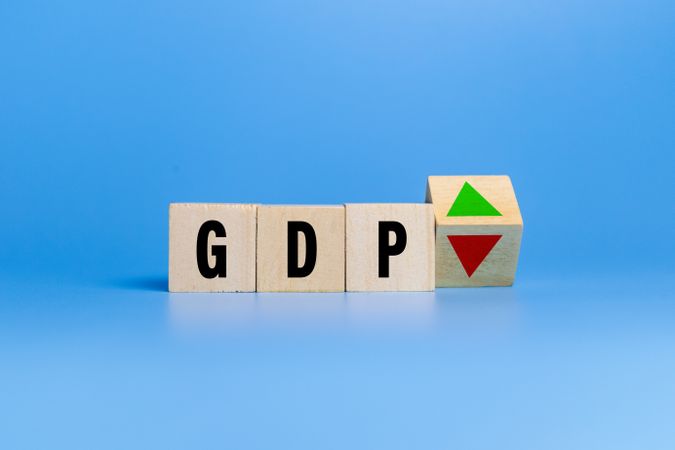 gross domestic product or GDP letter symbol with red down and green raise arrow on wooden blocks isolated on blue background. concept of growth business financial of country