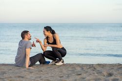 Happy couple in sportswear sitting on beach