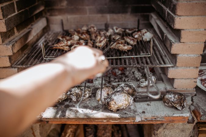 crop person cooking meat in barbecue