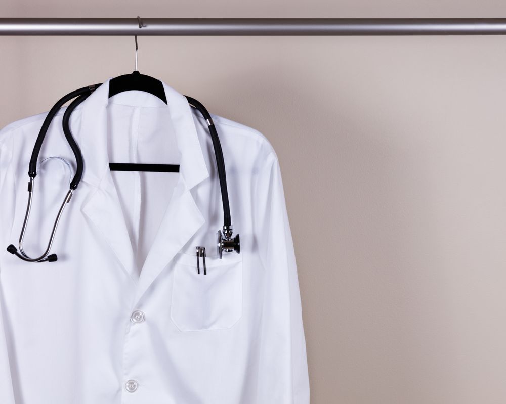 Medical consultation coat with stethoscope and pens on hanger