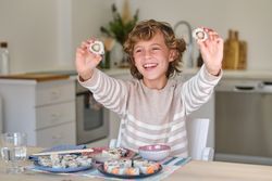 Cheerful boy eating sushi rolls at home