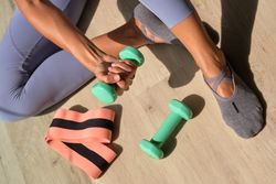 Sportswoman with dumbbell in hand sitting on floor