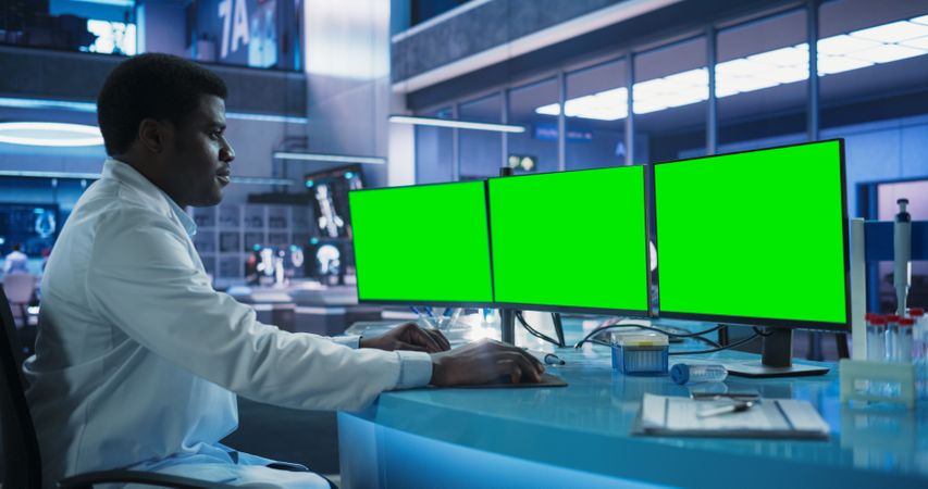 Cancer Research Center Medical Laboratory: Black Male Neuroscientist Using Desktop Computer With Green Screen Chromakey On Display.