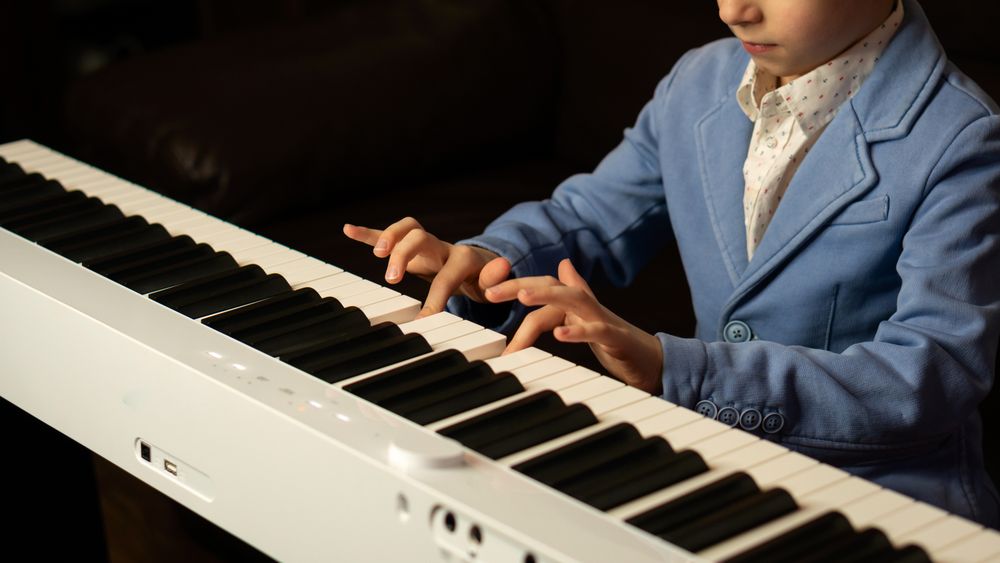 Side view of young boy playing digital piano