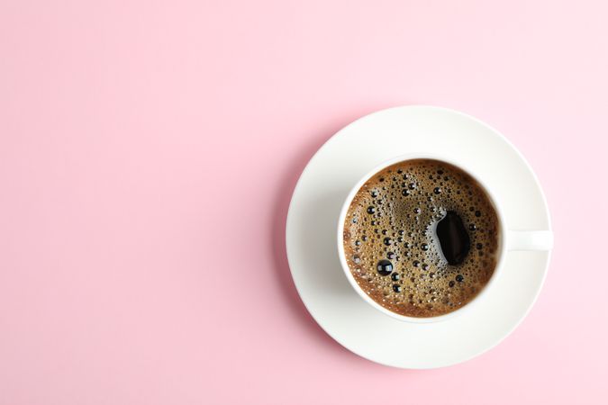 Cup of coffee on color background, space for text