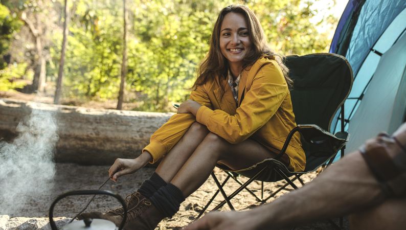 Beautiful woman sitting at campfire and looking at her boyfriend