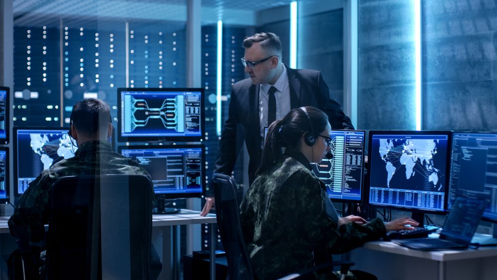 Team of Government Agents Tracking Fugitive with Boss's Survillance in Big Monitoring Room Full of Computers with Animated Screens.