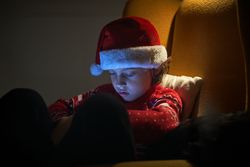 Cute boy in Santa hat sitting in armchair