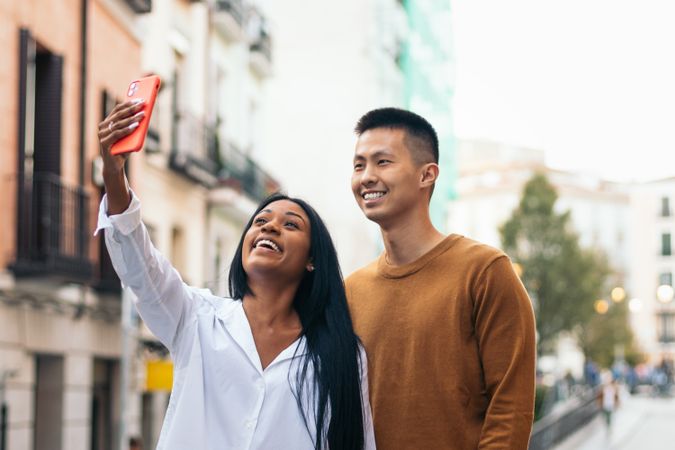 Asian man and Black Latina woman taking a selfie with smartphone