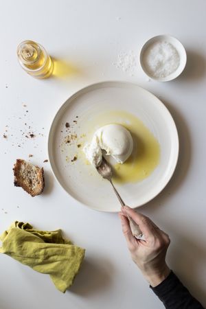 Crop hand taking cheese near bread and oil