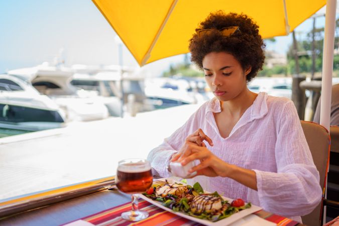 Woman putting salt on salad in cafe on pier