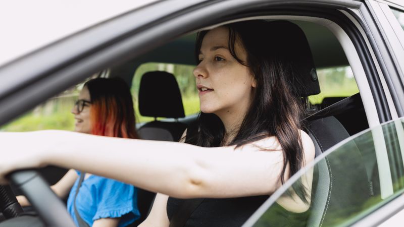 Two people happily travel by car, one of them driving, during a weekend getaway
