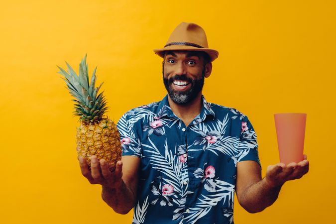 Friendly male holding up a pineapple and orange cup
