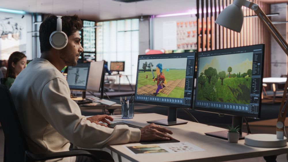 Indian Male Game Designer Using Desktop Computer With 3D modelling Software To Design Characters And World For Immersive Adventure Video Game.