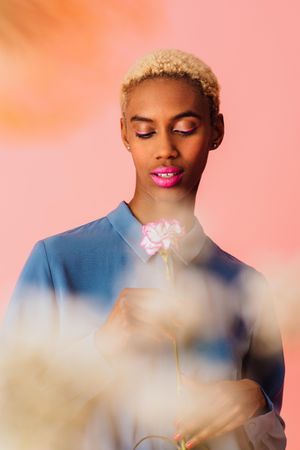 Black woman with short blonde hair looking at flower