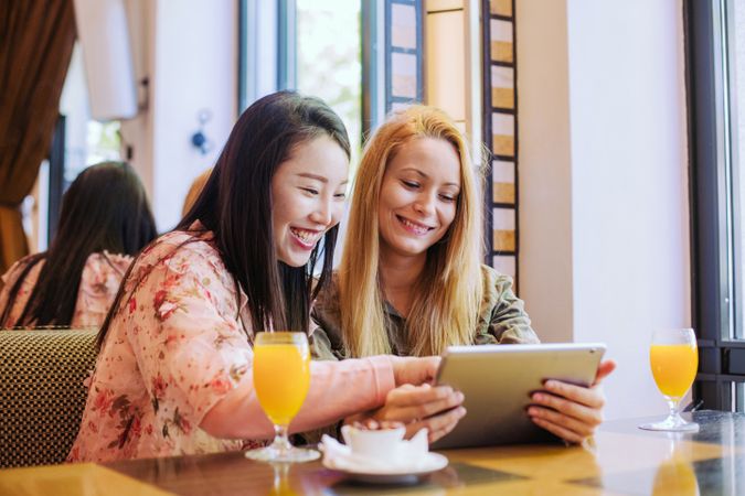 Female friends using tablet in cafe