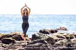Female doing yoga on rocky beach 4O7jg4