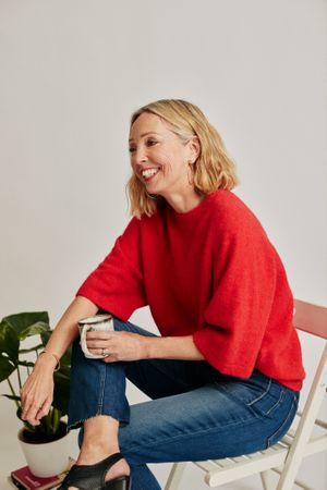Woman in red jumper on chair and smiling