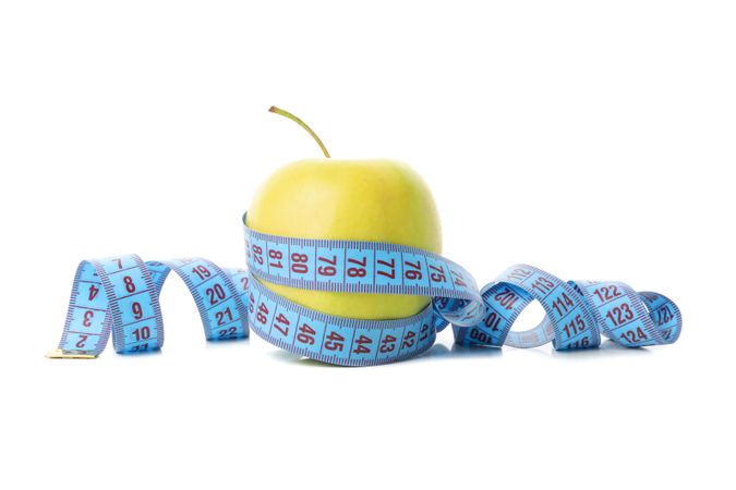 Measuring tape with apple isolated on light background