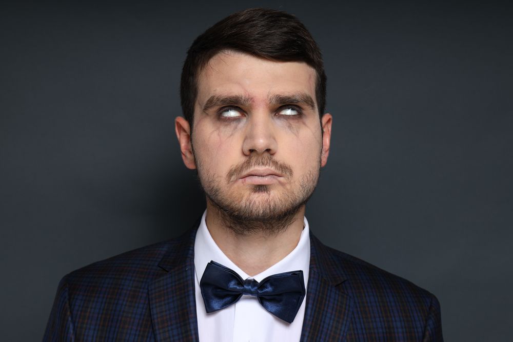 A man in a zombie costume on a dark background