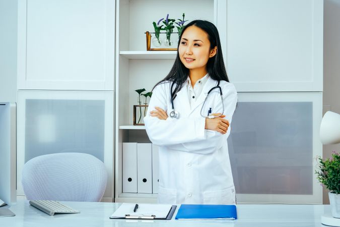 Proud Asian doctor in her office with arms crossed