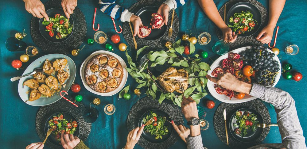 Group of people serving themselves food at festive table with candy canes and roasted pears