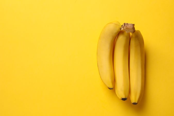 Banana cluster on yellow background. Fresh fruit