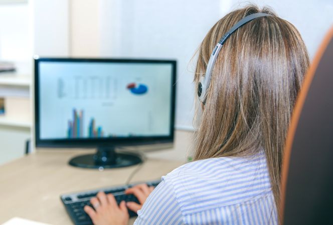 Back of woman working with charts on computer in office