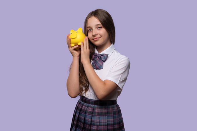 Young girl holding yellow piggy bank