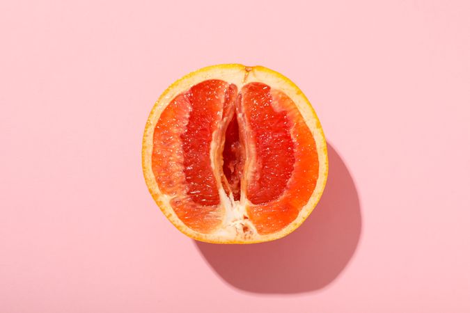Half of a grapefruit on a pink background.