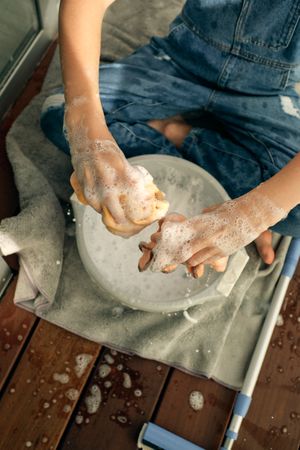 Unrecognizable child washing wipers in bucket