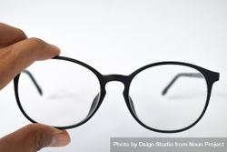 Glasses held by hand on plain background with copy space 0gXOZ3