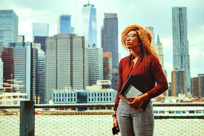 Professional Black woman holding her notebooks with Manhattan in the background