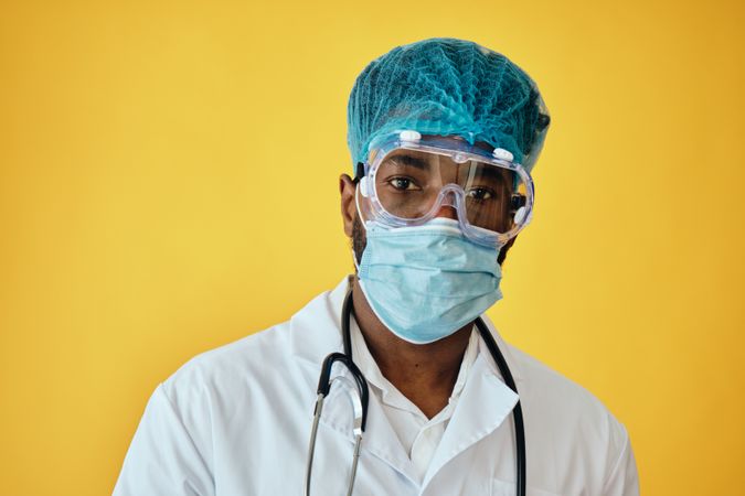 Portrait of Black medical doctor in light studio with full ppe gear