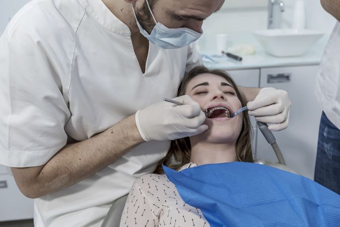 Dentist examining mouth of female teenage patient