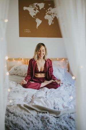 Young woman meditating on bed