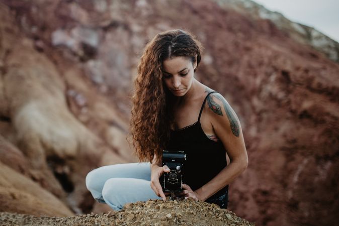 Woman with camera sitting on cliff