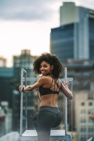 Fitness woman standing on rooftop and looking back