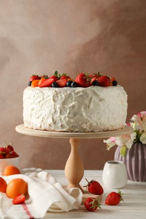 Composition with delicious berry cream cake on wooden table. Tasty dessert
