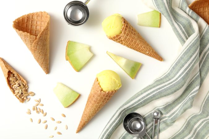 Ice cream cones with pieces of fresh melon on a plain background