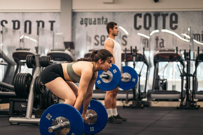 man and woman athlete training deadlift in a gym