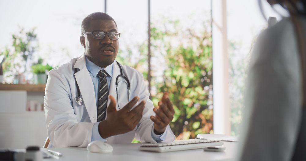 Black Doctor Speaking to an Anonymous Patient During a Consultation in Health Clinic.