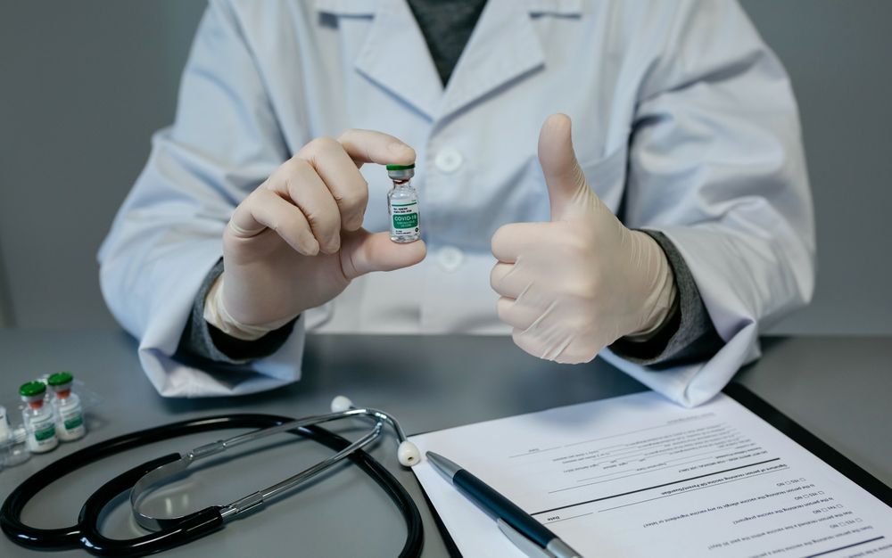Doctor with thumb up while showing coronavirus vaccine