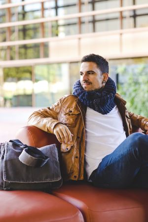 Stylish man sitting on red leather couch
